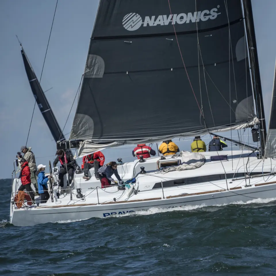 Equipaggio impegnato in una regata su barca a vela con vele nere Navionics